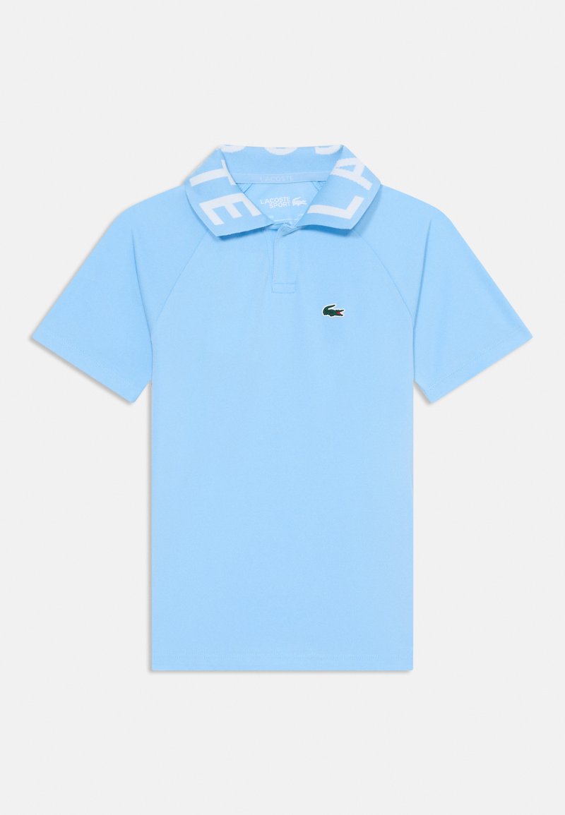 Polo shirt bleu clair avec un col à côtes portant le texte "LACOSTE" en blanc. Petit logo de crocodile vert sur la poitrine gauche.