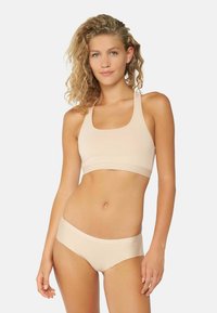 Soutien-gorge de sport beige avec de larges bretelles et un col carré, associé à un bas de bikini assorti. Tissu lisse avec un design sans coutures.