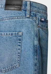 Ανοιχτό μπλε τζιν παντελόνι με μαύρη δερμάτινη ετικέτα DKNY Jeans, διαθέτει ραφή στην πίσω τσέπη και μια μικρή ετικέτα μάρκας στη μέση.