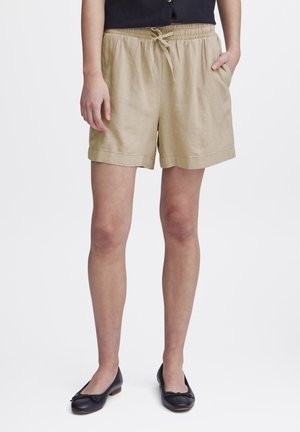 Beige lněné šortky s elastickým pasem na šňůrku, bočními kapsami a volným střihem. Lemování je ohrnuté pro ležérní vzhled.
