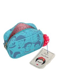 Borsa di tessuto blu con più volti di Frida Kahlo stampati, interni rosa a pois parzialmente aperti e un'etichetta attaccata che mostra un volto stilizzato di Frida.