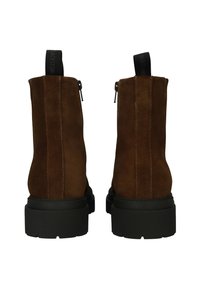 Botas de ante marrón hasta el tobillo con suelas de goma negras, cremalleras laterales y una lengüeta de tela en la parte trasera para facilitar su uso.