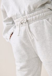 Hellgraue, strukturierte Sweatpants mit elastischem Bund und Kordelzug. Verfügt über seitliche Taschen und eine lockere Passform.