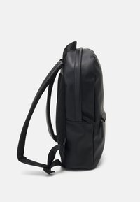 Lo zainetto nero presenta un esterno in sintetico liscio, spallacci imbottiti, tasca laterale e un design elegante e minimalista.