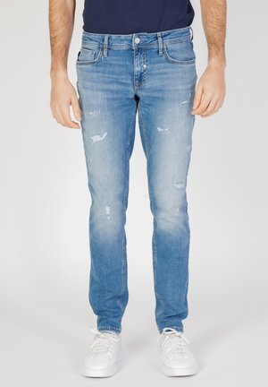 Jeans de color azul claro con un corte slim, que presentan áreas desgastadas, diseño clásico de cinco bolsillos, cierre de botón metálico y costura de un solo tono.