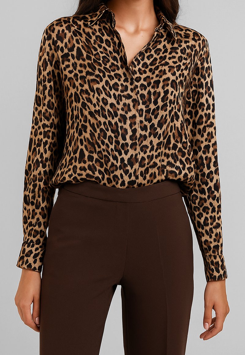 Blusa in stampa leopardata con colletto e chiusura a bottoni, dotata di maniche lunghe e una texture di tessuto morbida e liscia. Abbinata a pantaloni marroni.