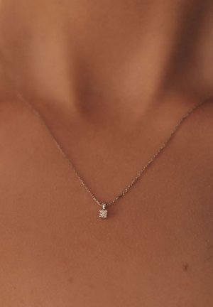 Zilveren ketting met een delicate schakel; beschikt over een kleine, vierkante hanger met een heldere, sprankelende steen in het midden.