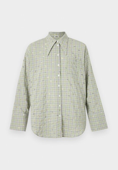 Green plaid button-up shirt with a pointed collar, long sleeves, and a chest pocket. Features white and black accents in the pattern.