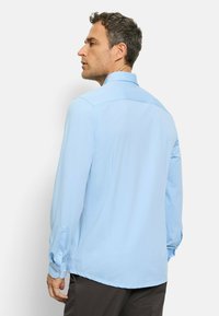 Hellblaues Langarmshirt mit strukturiertem Kragen, knöpfbaren Bündchen und glatter Oberfläche. Verfügt über eine zentrale Rückenpasse und einen geraden Saum.