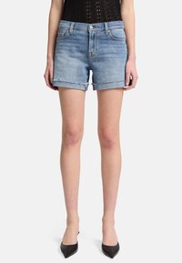Shorts in denim azzurro chiaro con orlo sfrangiato, design a cinque tasche e vestibilità slim. Abbinati a tacchi neri a punta e a un body nero.