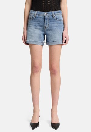 Shorts en denim bleu clair avec un ourlet effiloché, un design à cinq poches et une coupe slim. Associés à des escarpins noirs à bout pointu et un body noir.