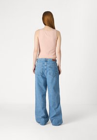 Ljusrosa ribbad linne med scallopkanter, parat med löst sittande ljusblå denimjeans, med bakfickor och en lädertag.