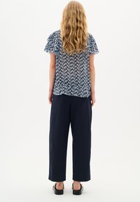 Pantaloni larghi blu abbinati a una maglietta a maniche corte con motivo blu e maniche arricciate. Tessuto morbido, vestibilità comoda.