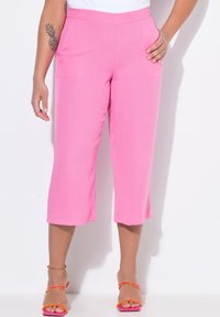 Roze, knielange broeken met een gladde textuur, voorzien van een aangesloten taille en een brede pijpenontwerp. Draagt het met kleurrijke sandaalbandjes.