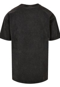 Black cotton t-shirt with a relaxed fit, short sleeves, and rounded neckline. Features visible stitching along the seams and a plain back.