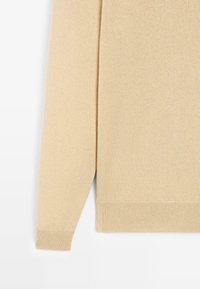 Béžový pletený svetr s žebrovanými manžetami a lemem. Měkká textura, dlouhé rukávy a střih rovného tvaru. Minimalistický styl bez ozdob.