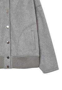 Graue Wolljacke mit Druckknöpfen, geripptem Saum und Seiten Tasche, die den rechten Ärmel und den unteren Frontbereich zeigt.