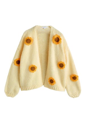 Cardigan crem tricotat cu aplicații mari de floarea-soarelui croșetate în galben și maro pe partea din față și pe mâneci, având un design lejer și deschis în față.