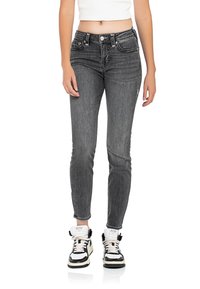 Jeans skinny in denim grigio con vita media, tasche frontali e un sottile dettaglio di cucitura. Abbinati a sneakers alte in bianco e nero.