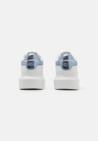 Bijele tenisice s metalik plavim detaljima, s glatkom sintetičkom kožom i logotipom straga. Zaobljeni vrh i debeli potplat.