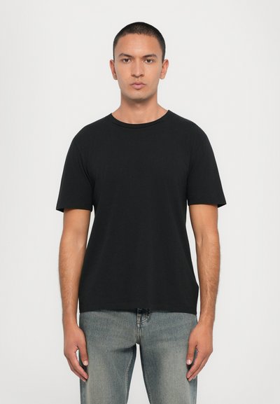 Czarny bawełniany t-shirt z okrągłym dekoltem i krótkimi rękawami, w połączeniu z jasnoniebieskimi dżinsami o prostym kroju i minimalnych detalach.