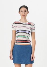Gestreifter Rippstrick-Oberteil mit roten, pinken, blauen und grünen Streifen, Rundhalsausschnitt; kombiniert mit einem blauen Jeans-Minirock.