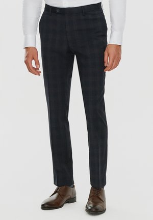 Granatowe spodnie w kratę o slim fit, z prostym przodem, zapięciem na guziki i bocznymi kieszeniami. W połączeniu z brązowymi skórzanymi butami.