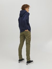 Felpa navy con tasca a marsupio e polsini a costine, abbinata a pantaloni cargo verde oliva con tasche laterali. Sneakers nere completano il look.