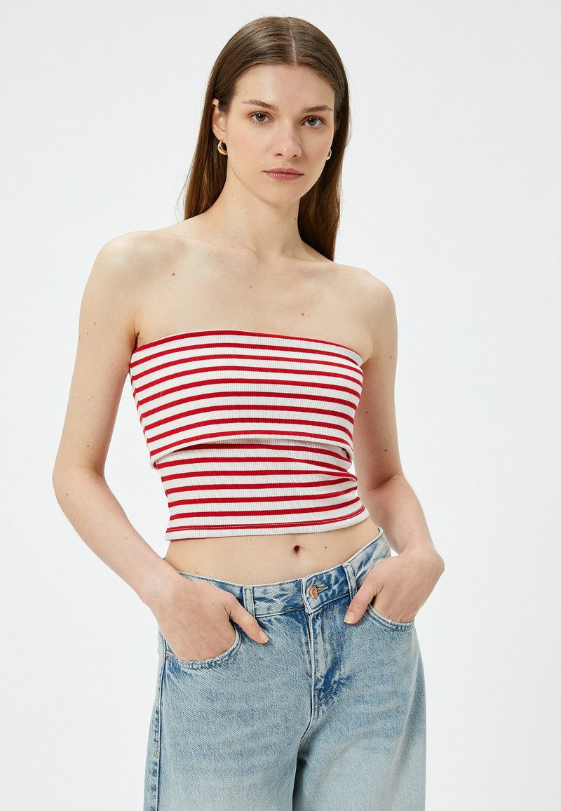 Top bandeau de rayas rojas y blancas en textura acanalada, combinado con jeans de tiro alto en azul claro, con un corte relajado y bolsillos frontales.