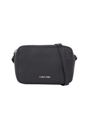 Czarna prostokątna torba na ramię z regulowanym paskiem i srebrnym logo Calvin Klein na środku przodu.