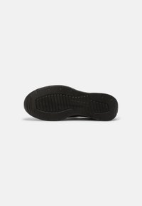 Fekete sneaker talp, amely texturált gumimateriálból készült, vízszintes barázdákkal és mintákkal a tapadás érdekében. Kerekded forma, megerősített élekkel.