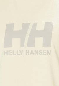 Logotipo de Helly Hansen con doble H estilizada en gris y texto sobre un fondo de tela beige claro.