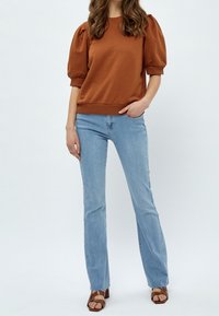 Brown puff-sleeve sweater, light blue flared jeans, brown strappy sandals. Smooth texture and relaxed fit with ribbed cuffs and hem.