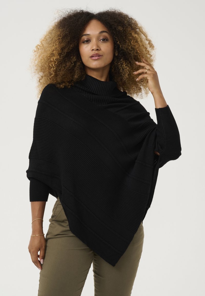 Poncho nero in maglia con collo a lupetto a coste, caratterizzato da motivi a strisce diagonali. Vestibilità ampia con maniche lunghe e orlo asimmetrico.