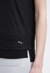 Svart kortärmad t-shirt med en avslappnad passform, iögonfallande med en fin vit broderad logotyp nära fållen och sidofack för ökad rörelse.