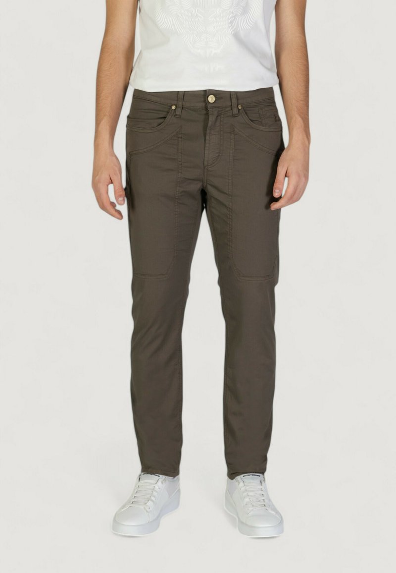 Pantaloni slim-fit marrone scuro con una texture liscia, dotati di tasche frontali e chiusura con bottone, abbinati a sneakers bianche.