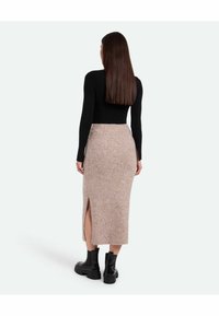 Fustă midi tricotată bej, cu o fanta laterală; asortată cu un top negru cu mânecă lungă, ajustat, și botine negre. Textură netedă, design casual.