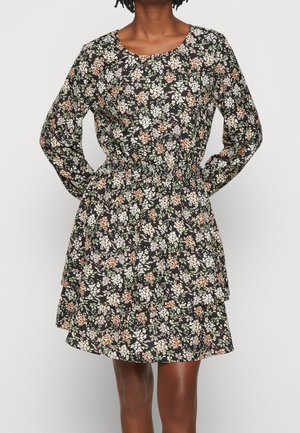 Bloemenjurk met lange mouwen, geëffende taille en gelaagde rok, met een zwarte achtergrond en witte, oranje en groene bloemenpatronen.