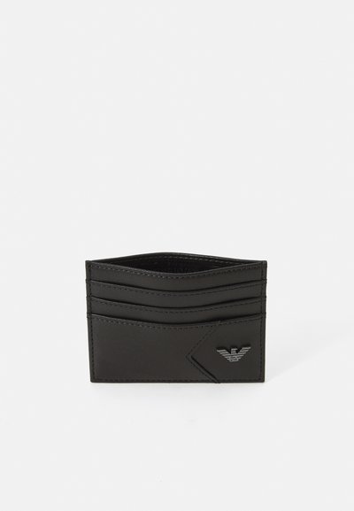 Svart läderkortfodral med flera kortfack och en texturerad logodetalj. Slimmad rektangulär form med sticksöm och slät yta.