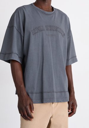 Dunkelgraues übergroßes T-Shirt aus Baumwolle, mit geripptem Rundhalsausschnitt, überschnittenen Schultern und gesticktem "Alpha Industries"-Logo.