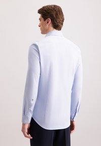 Camicia a maniche lunghe azzurro chiaro realizzata in tessuto morbido. Presenta un colletto a punta e polsini buttoned, con orlo curvo e vestibilità sagomata.