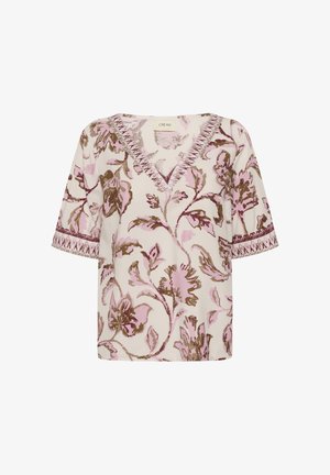 Blouse crème à col en V avec motif floral rose et marron, manches courtes et bordure décorative le long de l'encolure et des bords des manches.