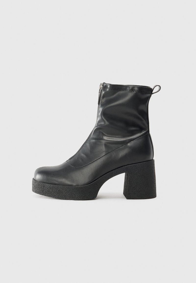 Botte noire en cuir mi-mollet avec talon plateforme épais et texturé, fermeture éclair latérale et languette à l’arrière.