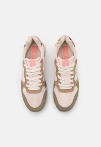 Jasnobrązowe i oliwkowozielone trampki z siateczkowym i zamszowym materiałem, z białymi sznurowadłami, różowymi akcentami oraz kwiatowym wzorem na pięcie.
