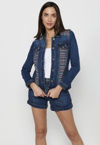 Jeans jakna v temno modri barvi z vezenimi poudarki na ramenih, z gumbom zapiranja, dvema žepoma na prsih in prilegajočim dizajnom.