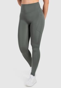 Vysoké sportovní legíny v olivově zelené barvě, se hladkým povrchem, kontrastními švy a přiléhavým střihem.