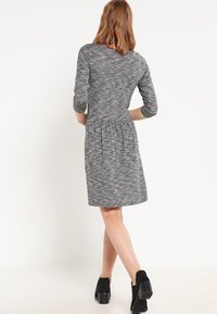Szara dzianinowa sukienka z rękawami do połowy przedramienia, dopasowanym gorsetem i marszczonym dołem. Posiada fakturowany wzór oraz okrągły dekolt.