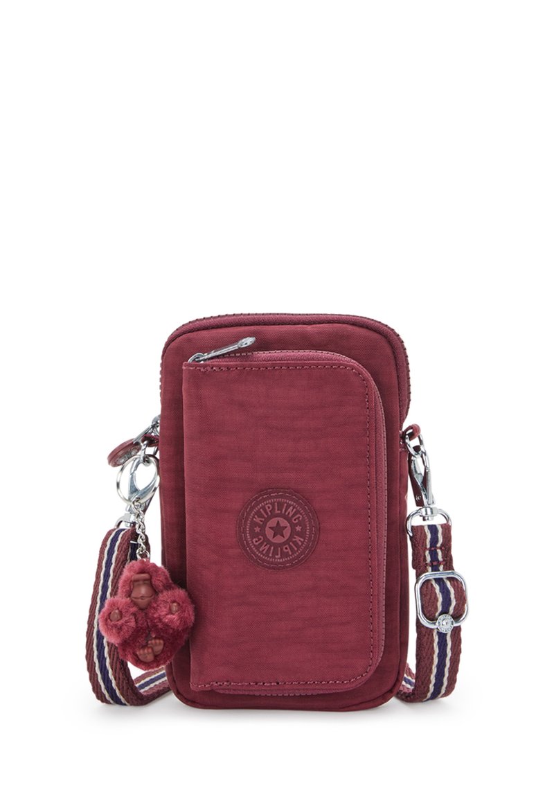 Piccola borsa a tracolla color bordeaux con tasca anteriore con zip, tracolla regolabile a righe e portachiavi a forma di scimmia peluche attaccato.