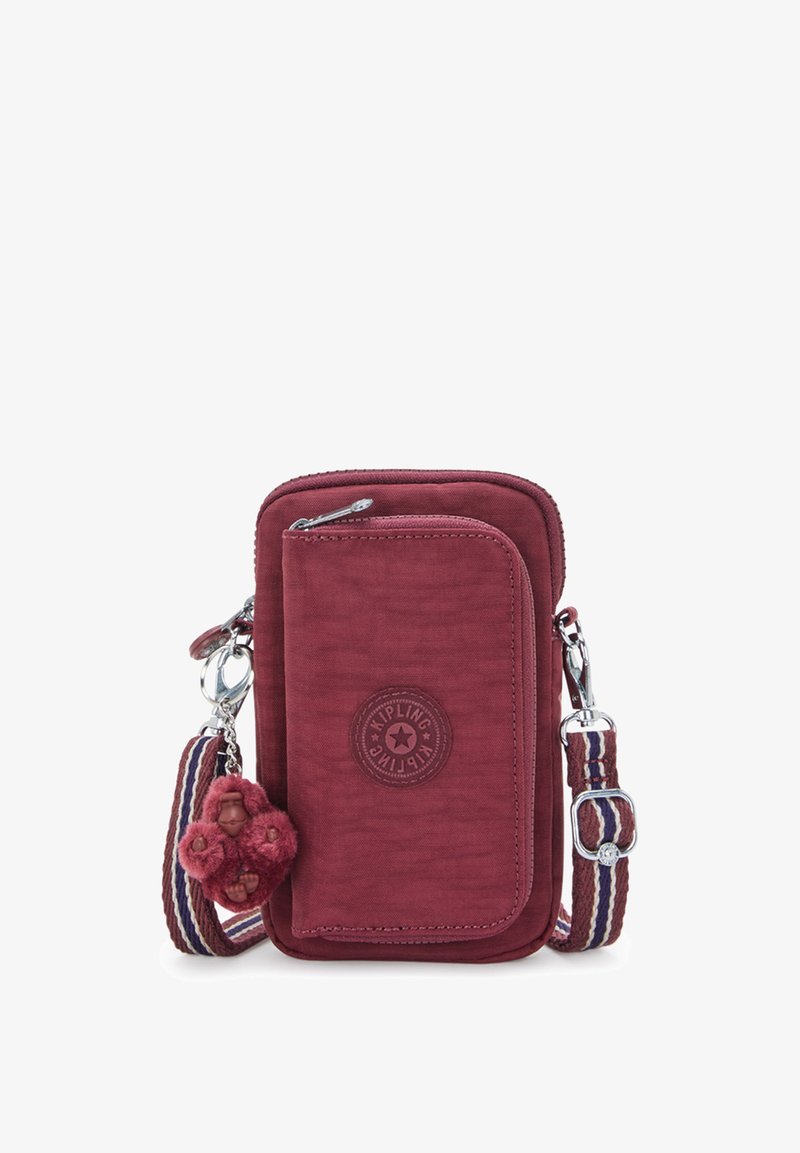 Piccola borsa a tracolla color bordeaux con tasca anteriore con zip, tracolla regolabile a righe e portachiavi a forma di scimmia peluche attaccato.