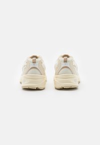 Beige og hvite sneakers med mesh og glatte paneler, rund tå, polstret krage og gummi såle. Subtile beige detaljer på siden.
